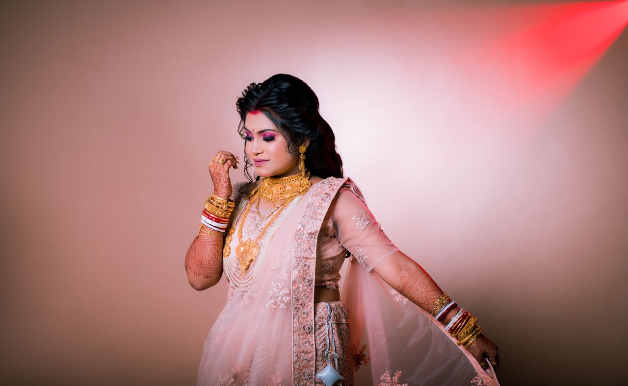 ours-journey A beautiful Indian bride in traditional jewelry and attire with henna tattoos, captured elegantly.
