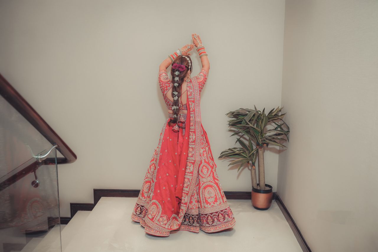 The Art of Drawing Readers In: Your attractive post title goes here Elegant Indian bride posing indoors, wearing vibrant red lehenga with intricate designs.