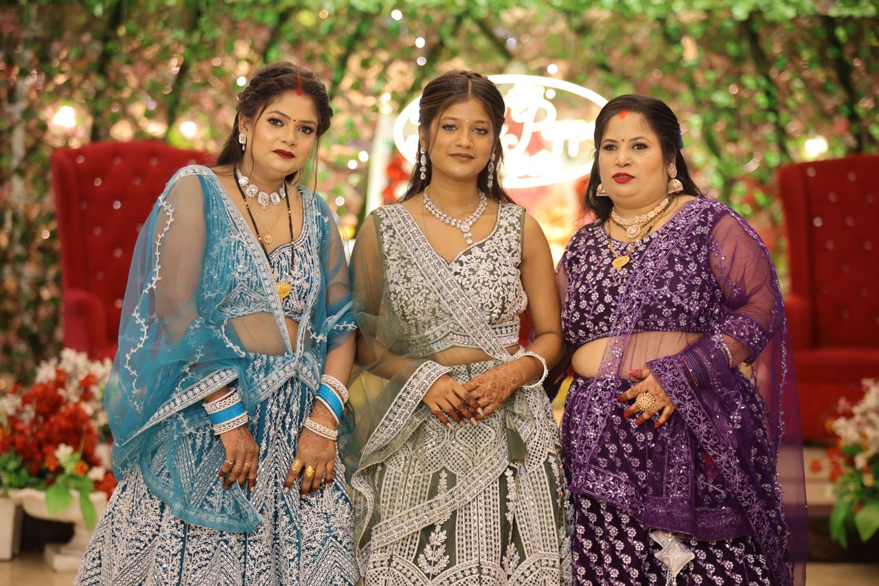 gallery-2 Three women in beautiful traditional outfits posing at a decorated indoor event.